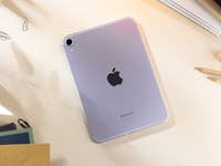 Apple iPad Mini 7 showing the back with logo on a desk surrounded by papers and pencils.