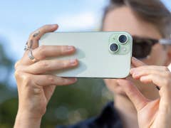 A person taking a picture with the Apple iPhone 15