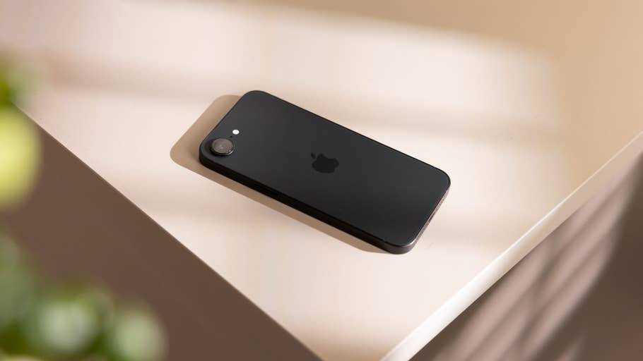 A black Apple iPhone 16e placed on a light-colored surface.