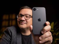 A person holding an Apple iPhone 16e, showcasing its back design with the Apple logo.