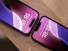 Two iPhones displaying the time: 18:15 and 18:13 on a wooden surface.