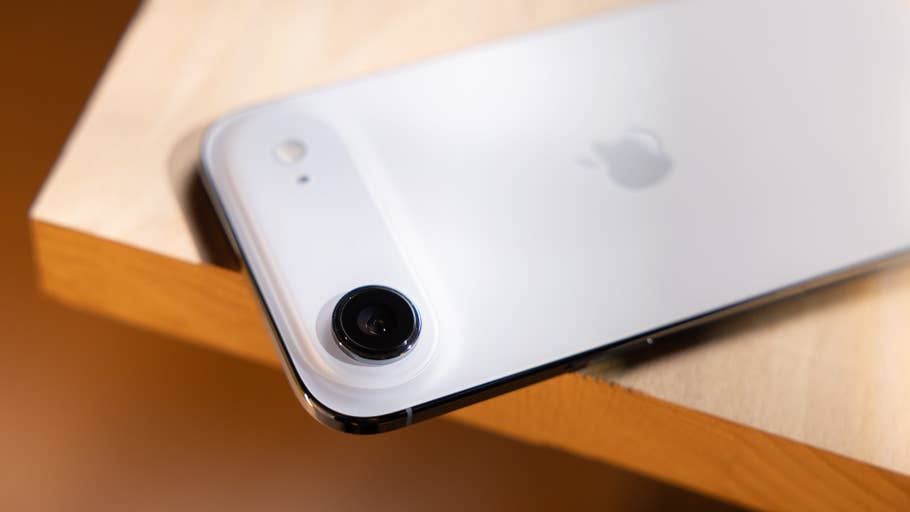 Close-up of an Apple iPhone Air lying on a wooden surface showing the camera and logo.