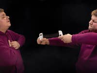 A man in a purple hoodie is split into two mirrored images, each holding one end of a game controller, as if pulling it apart.