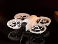 A DJI Neo drone is displayed on a reflective surface with soft lighting.