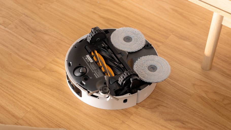 A Dreame X50 Ultra robot vacuum cleaner with its mopping pads, placed on a wooden floor.
