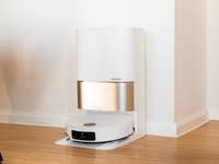 A Dreame X50 Ultra robot vacuum docked at its charging station in a modern interior.