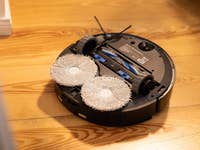 A robotic vacuum cleaner with mopping pads on a wooden floor.