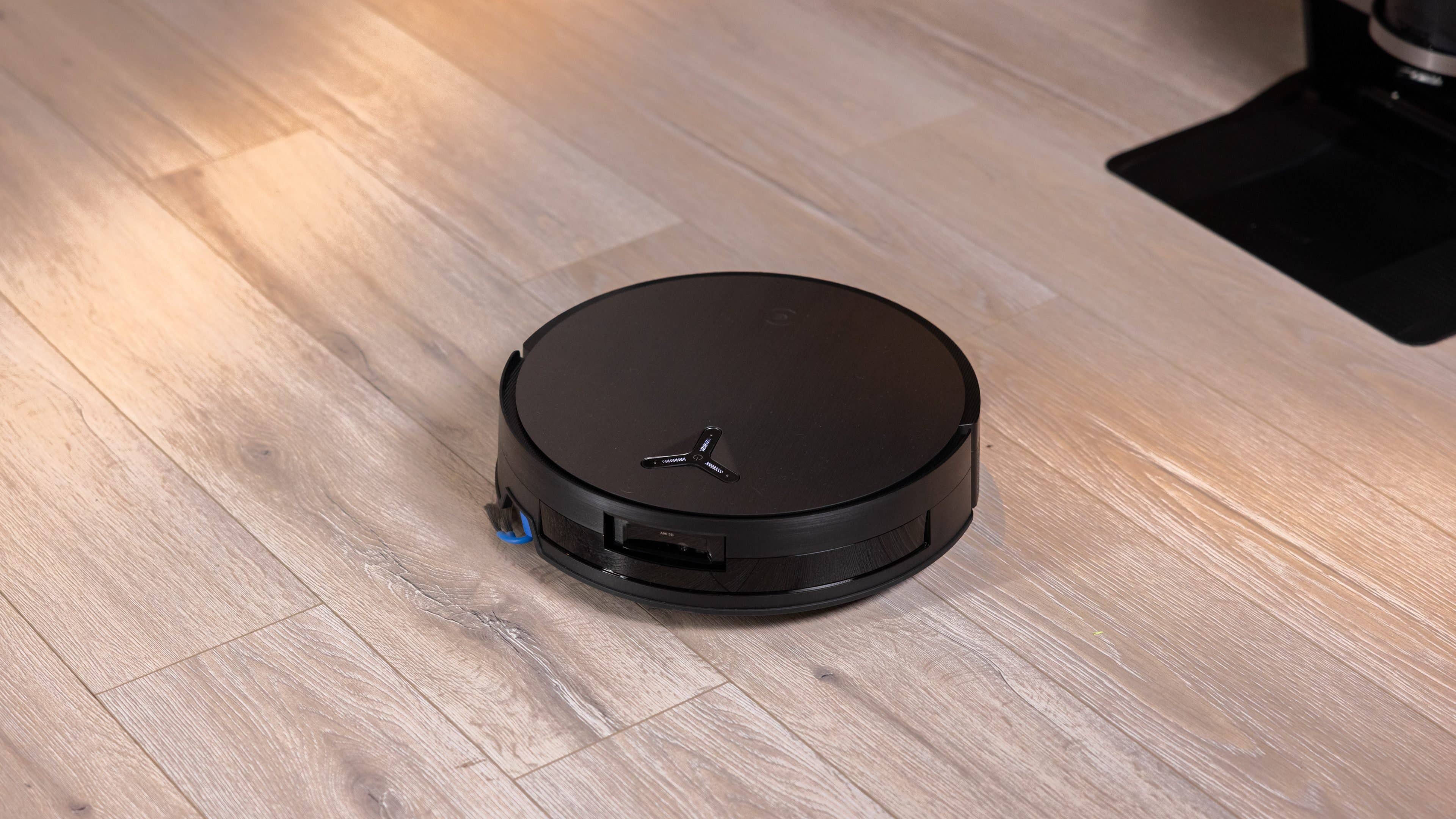 A black ECOVACS DEEBOT X11 OmniCyclone robotic vacuum on a wooden floor. A black ECOVACS DEEBOT X11 OmniCyclone robotic vacuum on a wooden floor.