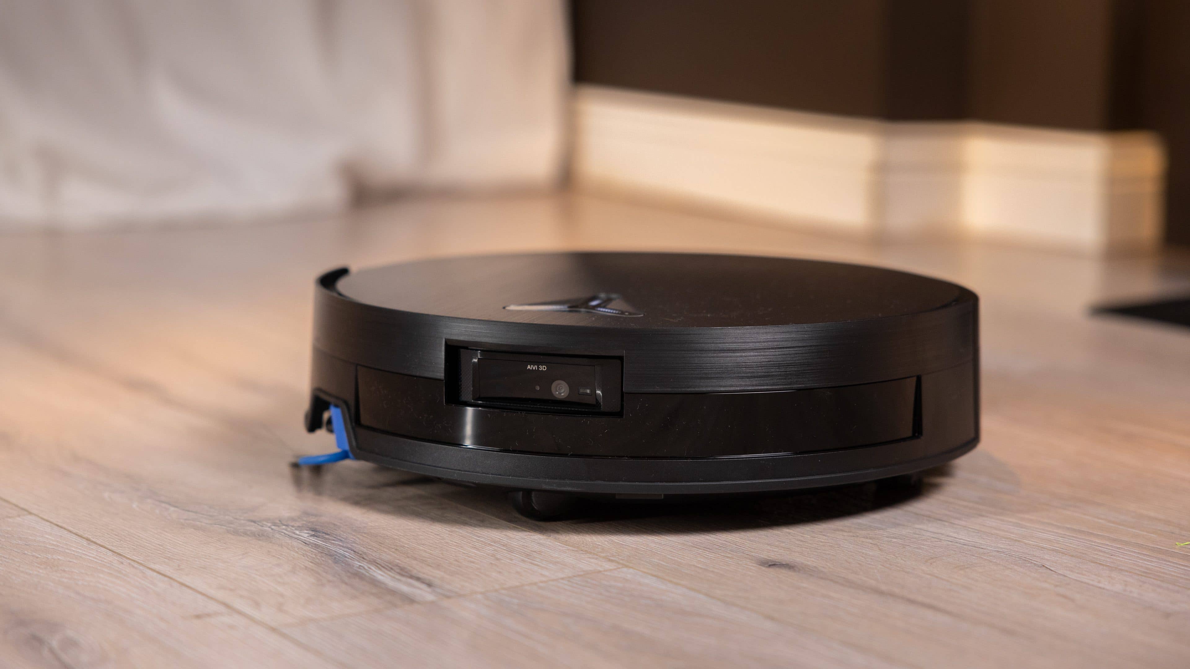 A black robotic vacuum cleaner on a wooden floor. A black robotic vacuum cleaner on a wooden floor.