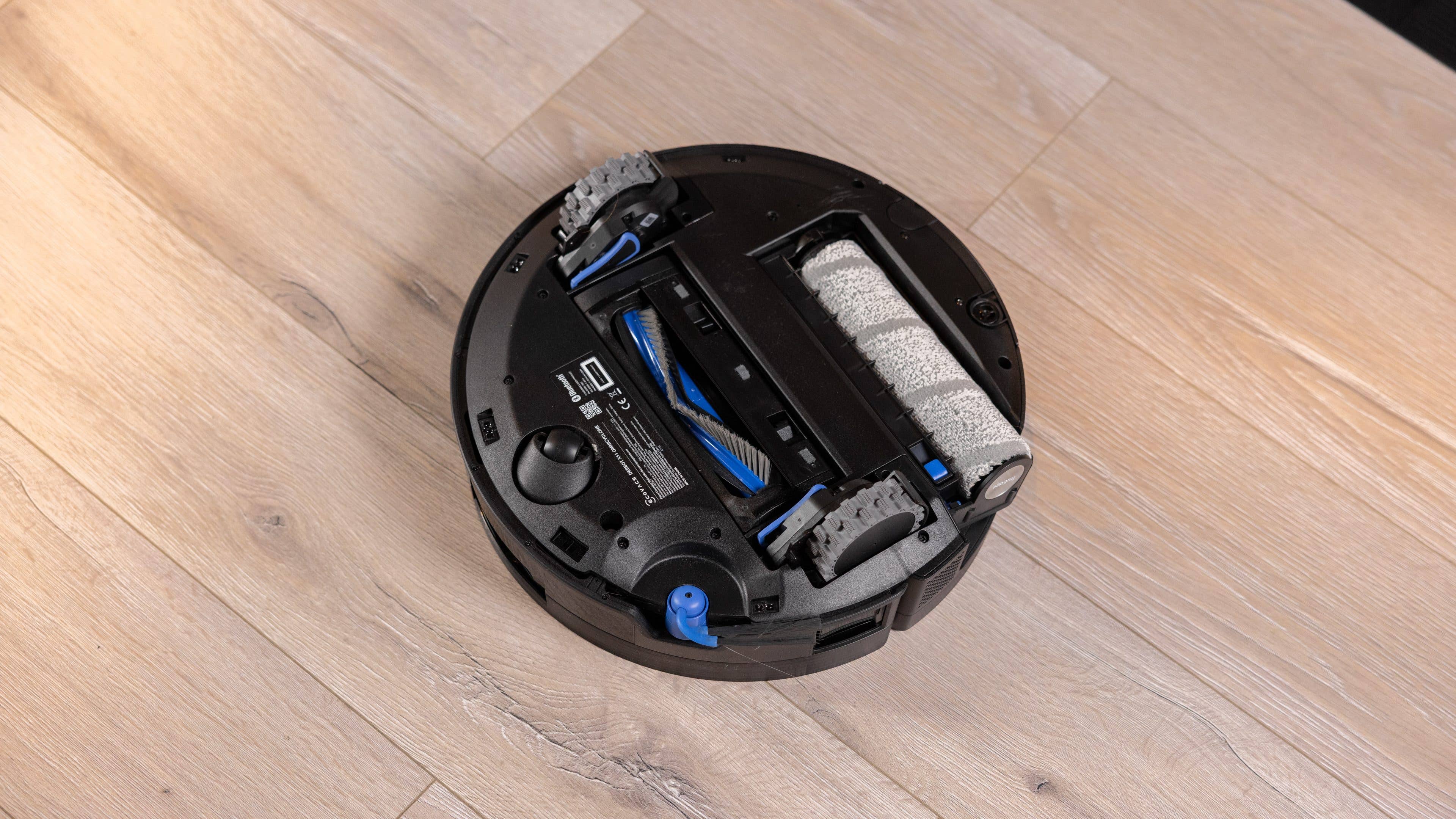 A black Ecovacs Deebot X11 Omniclone robotic vacuum on wooden flooring. A black Ecovacs Deebot X11 Omniclone robotic vacuum on wooden flooring.
