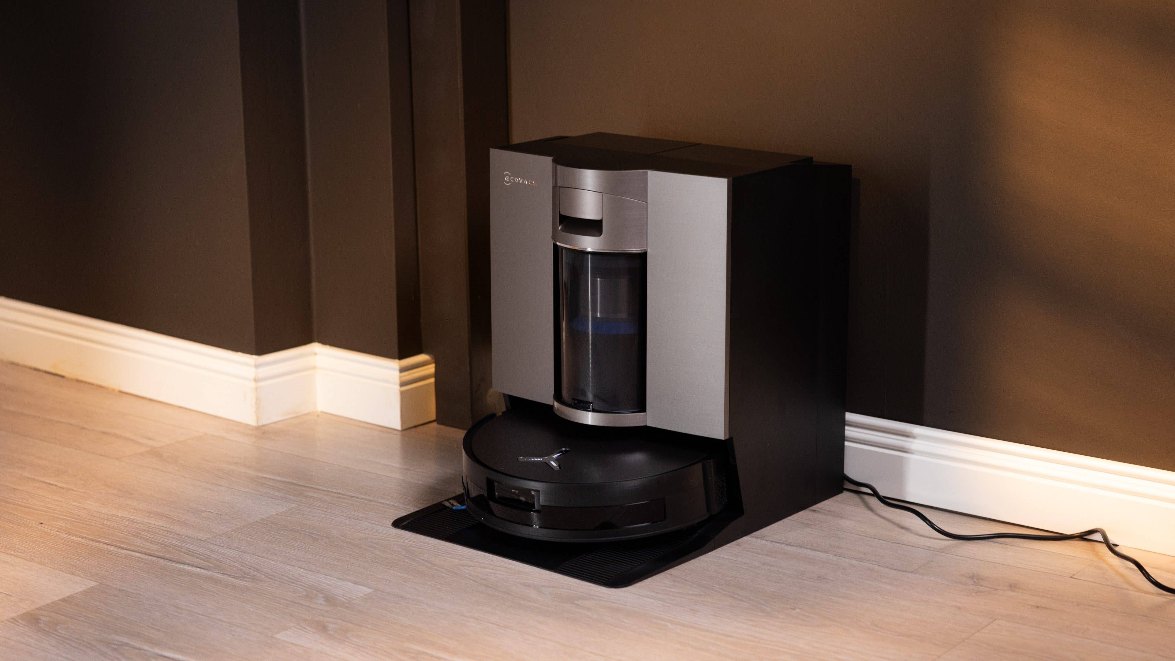 A modern Ecovacs Deebot X11 Omniclone robotic vacuum docked against a dark wall.