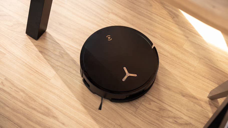 A black Ecovacs Deebot X8 Pro Omni robot vacuum cleaner on a wooden floor.