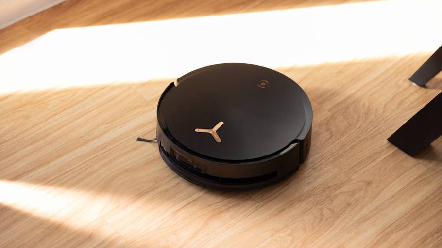 A black Ecovacs Deebot X8 Pro Omni robot vacuum cleaner on a wooden floor.