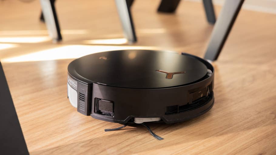 A black Ecovacs Deebot X8 Pro Omni robot vacuum cleaner on a wooden floor.