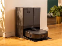 A Eufy X10 Pro Omni robotic vacuum docked next to a plant in a sunlit room.