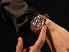 Close-up of a person wearing a Garmin Lily 2 smartwatch, showing the floral pattern on the watch face.