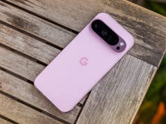 A Google Pixel 9 Pro smartphone in pink color resting on a wooden table.