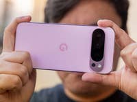 A person holding a Google Pixel 9 Pro smartphone, displaying its pink back and camera setup.