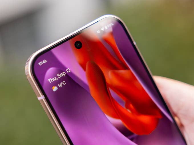 Close-up of a hand holding a Google Pixel 9 Pro smartphone displaying the date and weather.