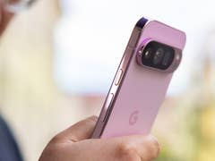 A close-up of a Google Pixel 9 Pro smartphone in a person's hand, featuring a pink design and dual cameras.