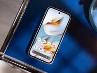 A Google Pixel 9a smartphone displayed on a blue surface next to a blue lamp.