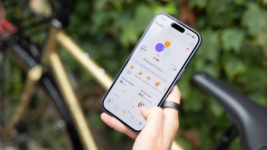 A person holding a smartphone displaying health statistics with a bicycle in the background.