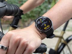 A close-up of a Huawei Watch GT 6 Pro on a person's wrist while holding a bicycle handlebar.