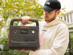 A person holding a Jackery Explorer 1000 portable power station outdoors.