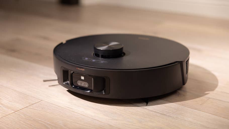 A black robotic vacuum cleaner on a wooden floor.
