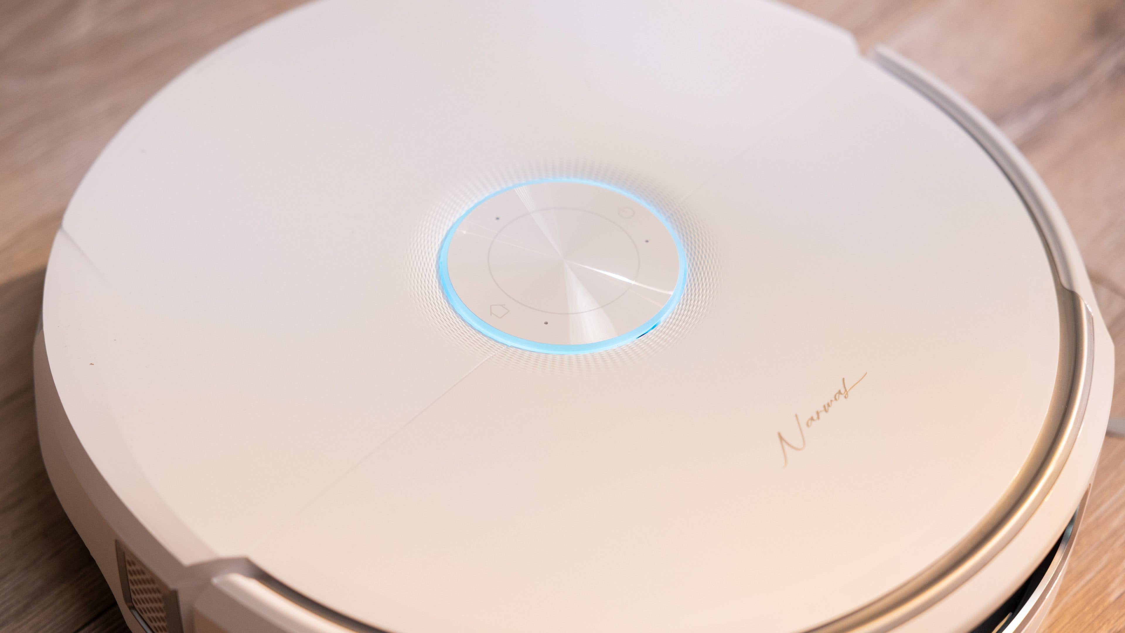 A sleek, round robotic vacuum cleaner with a blue light indicator on top.