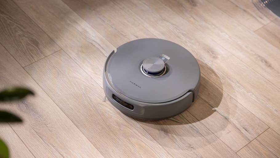 A grey robot vacuum cleaner on a wooden floor.