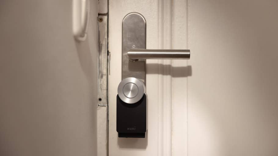 A Nuki Smart Lock Pro on a door, with a silver handle and locking mechanism.