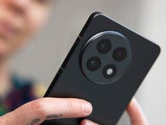 A person holds a OnePlus 13R smartphone displaying its rear camera design.