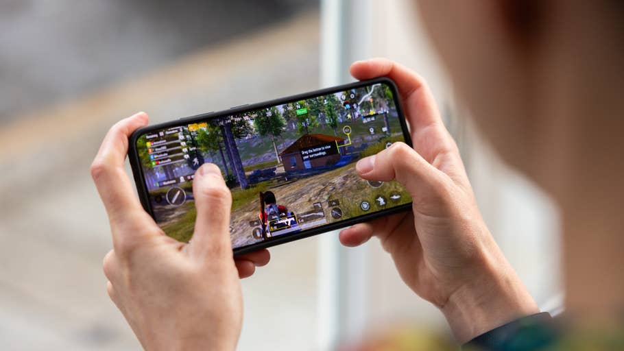 A person playing a mobile game on a smartphone, showcasing the OnePlus 13Ru0027s gaming capabilities.