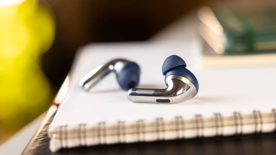 Close-up of the OnePlus Buds Pro 3 wireless earbuds on a notebook.