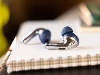 Close-up of OnePlus Buds Pro 3 wireless earbuds on a notebook.