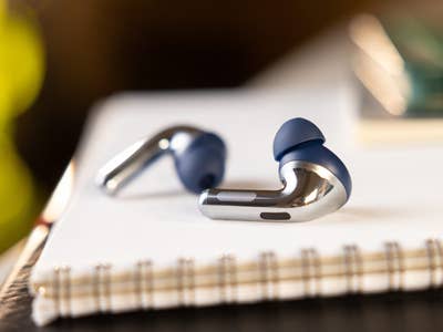 Close-up of OnePlus Buds Pro 3 wireless earbuds on a notebook.