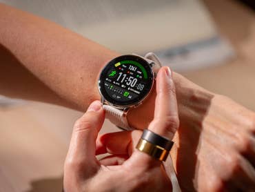 A person checking the OnePlus Watch 3 on their wrist, displaying time and fitness stats.