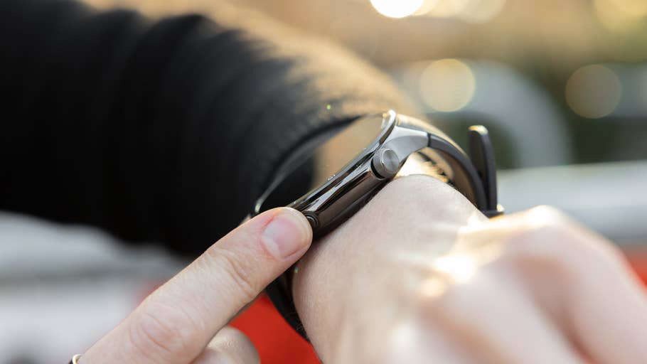 A close-up of a person adjusting a OnePlus watch on their wrist.