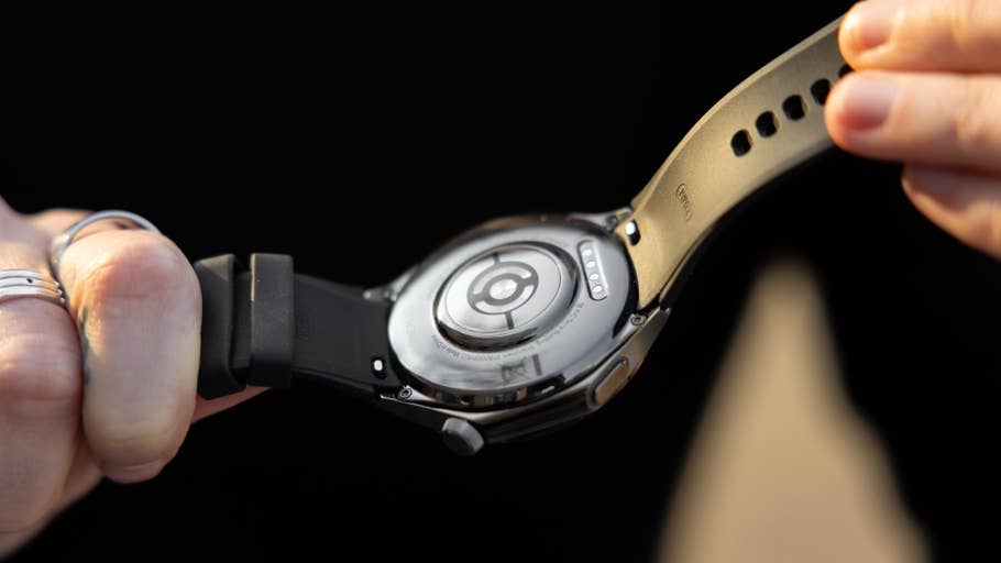 A person holds a black OnePlus Watch 3, showing its back and strap details.