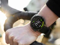 A close-up of a wrist wearing a OnePlus watch while holding a bicycle handlebar, displaying the time and metrics.