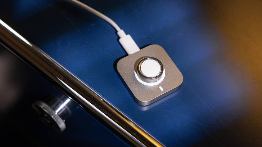 A charging dock for the Oura Ring 4 on a reflective surface.