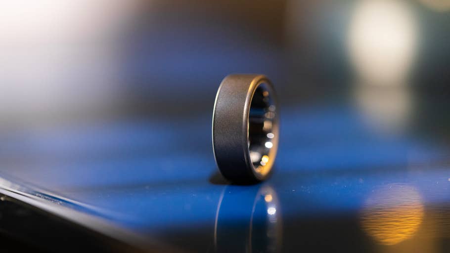 A black Oura Ring 4 resting on a reflective surface.