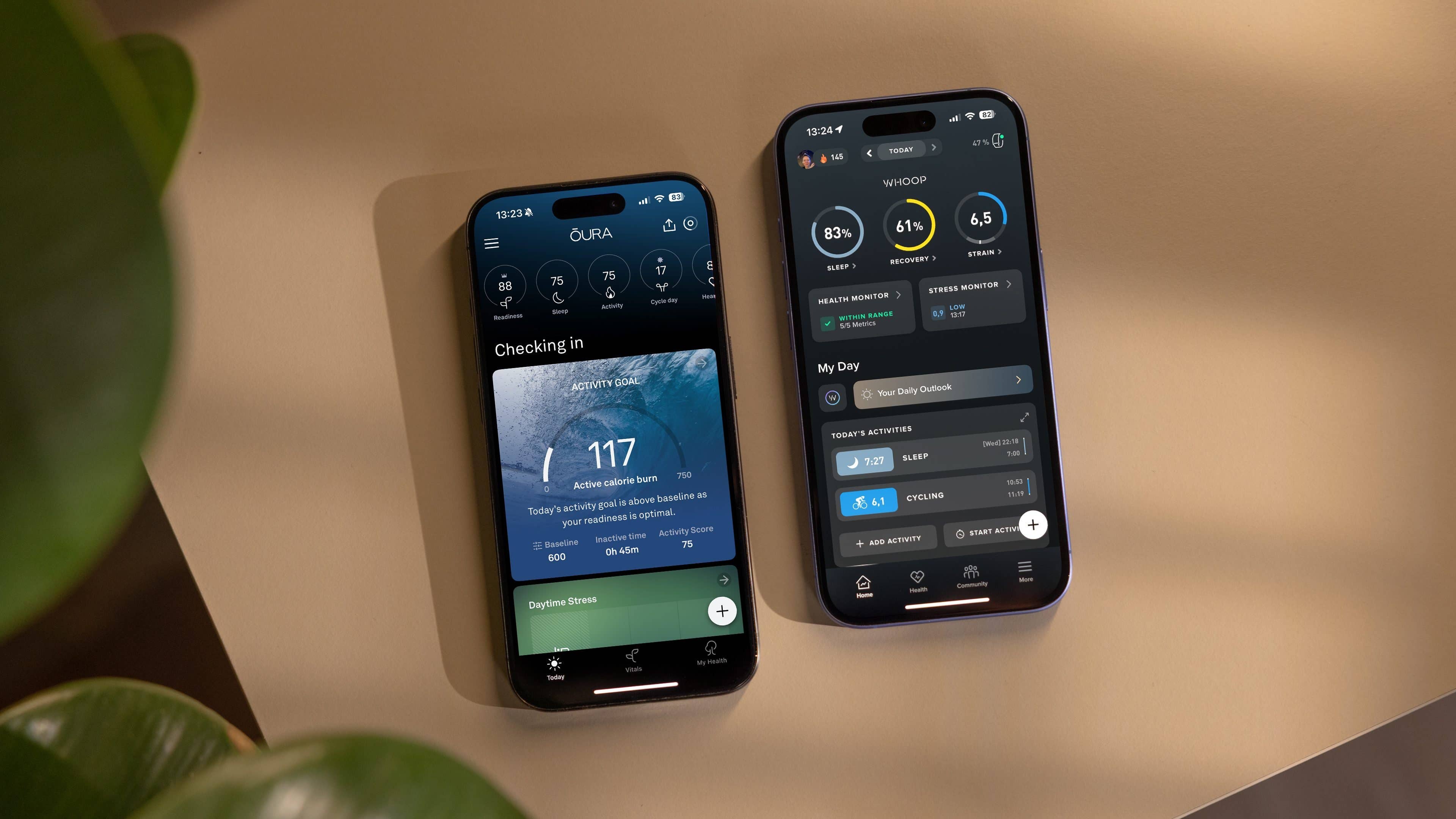 Two smartphones displaying health tracking apps: Oura on the left, Whoop on the right, on a light surface.