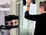 A person lifting weights in front of a Peloton display for cross training.