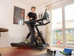 A person running on the Peloton Tread in an apartment