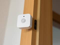 A Philips Hue motion sensor mounted on a wooden door frame.