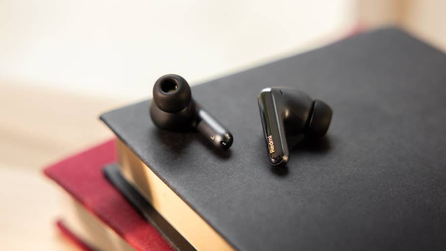 Two Redmi Buds 6 Pro wireless earbuds on a black notebook.