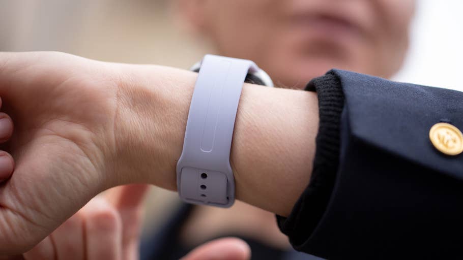 A close-up of a hand wearing a purple Redmi Watch 5 on a wrist.