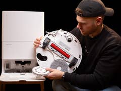 A person displaying the bottom of the Roborock Q Revo MaxV robot vacuum cleaner.
